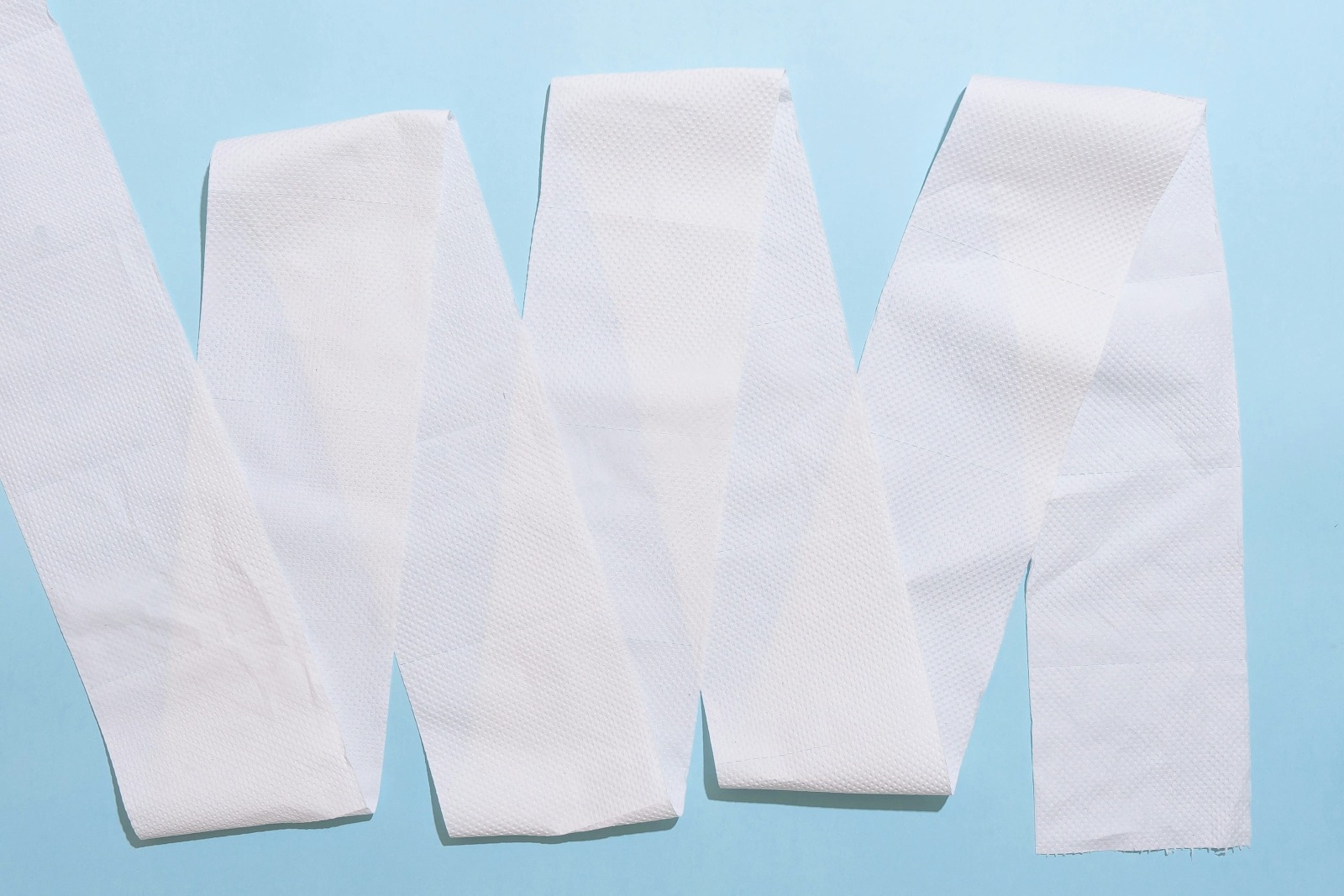 Folha grande de lenço umedecido ou papel toalha sobre uma superfície azul.